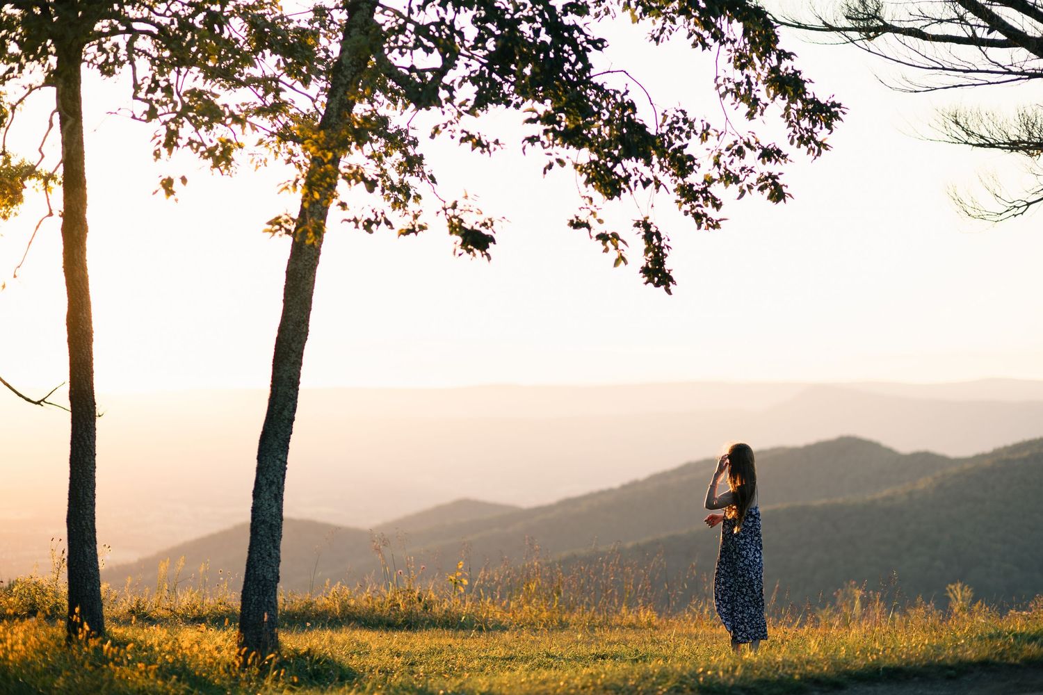 Couple embraces on rocky mountain peak overlooking vast landscape under cloudy blue sky.
