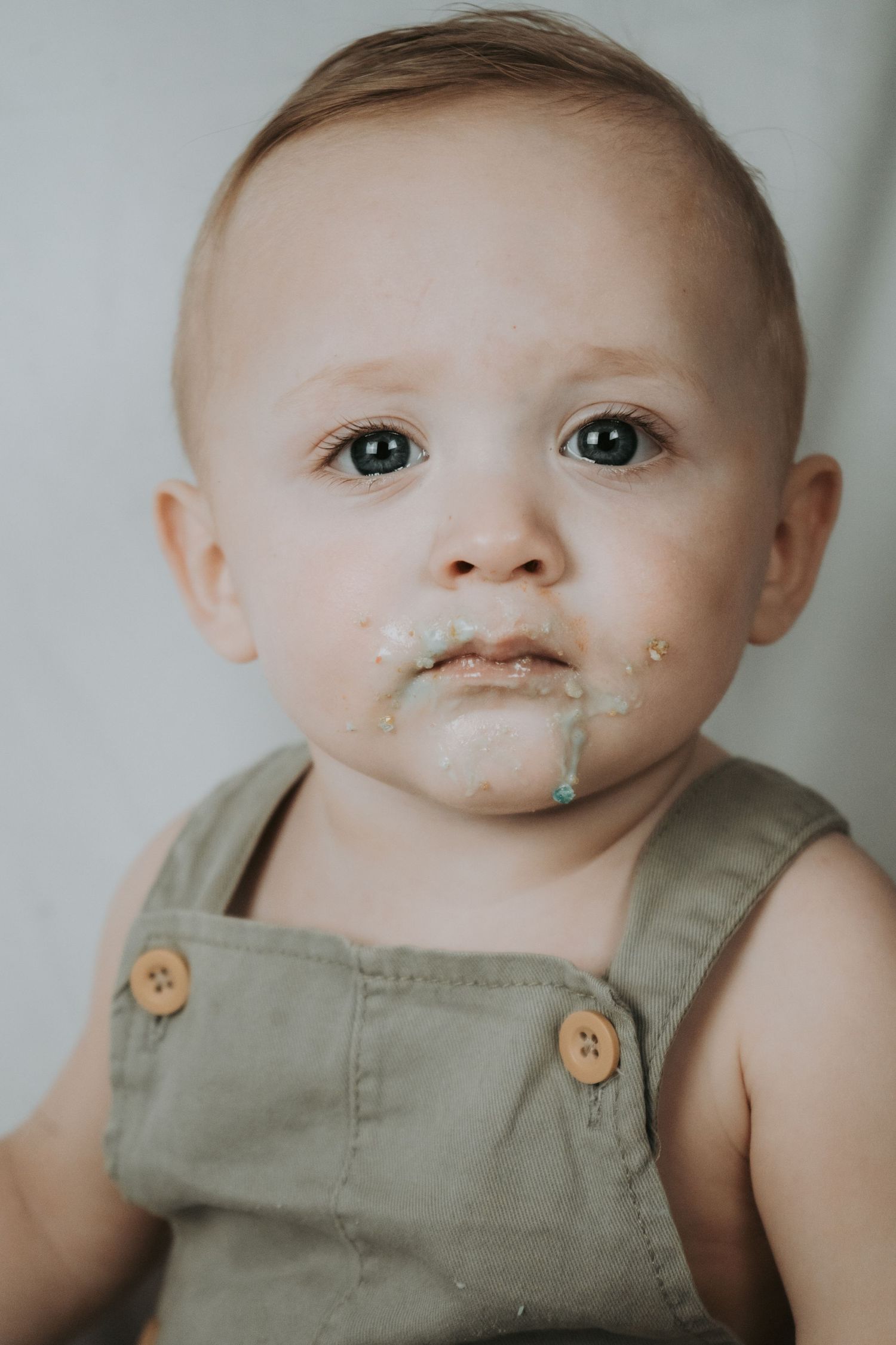 Close-up portrait series showing a baby in green overalls with messy face.