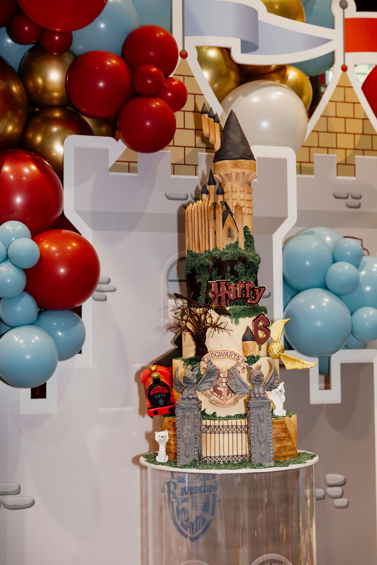 Party decorations featuring red and light blue balloons with castle-themed centerpieces on clear pedestals.