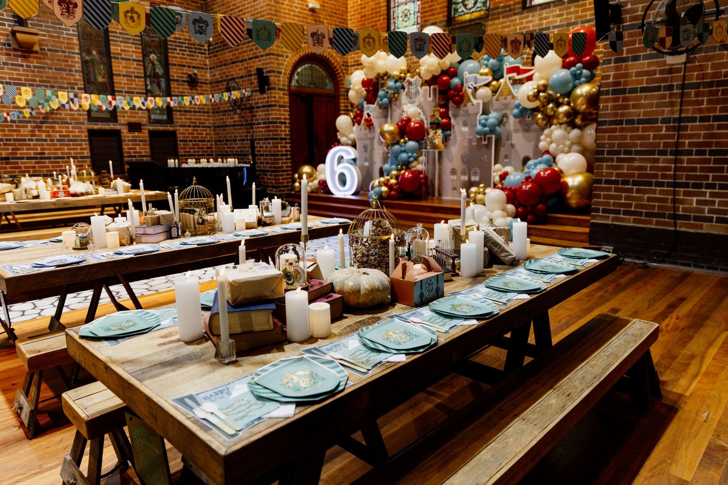 Rustic restaurant interior with exposed brick walls, string lights, and long wooden communal dining tables set for service.