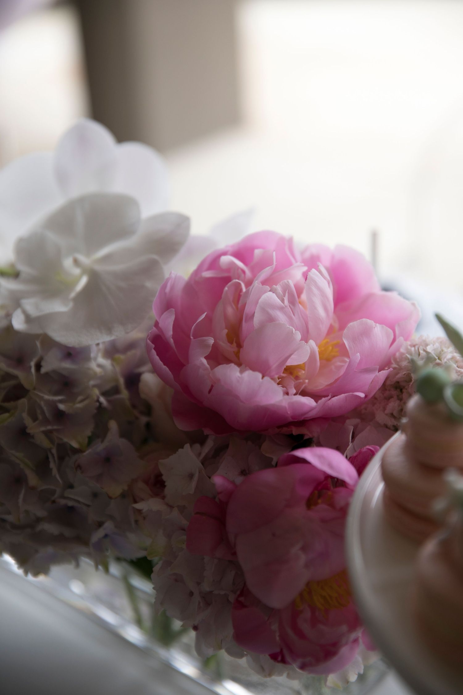 A delicate arrangement of pink peonies and white flowers in soft focus.