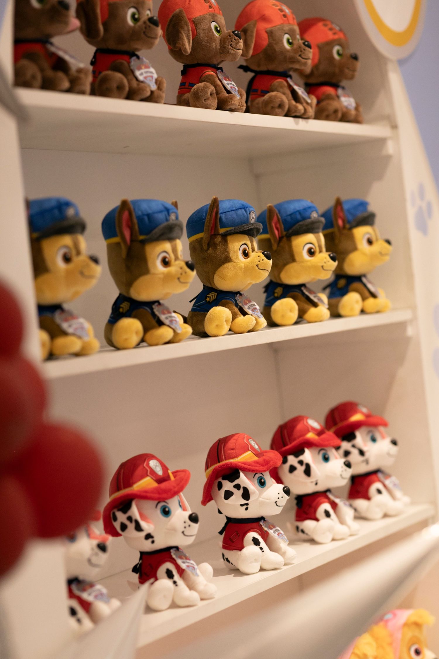 Multiple rows of identical Paw Patrol plush toys featuring Chase and Marshall characters displayed on white retail shelves.