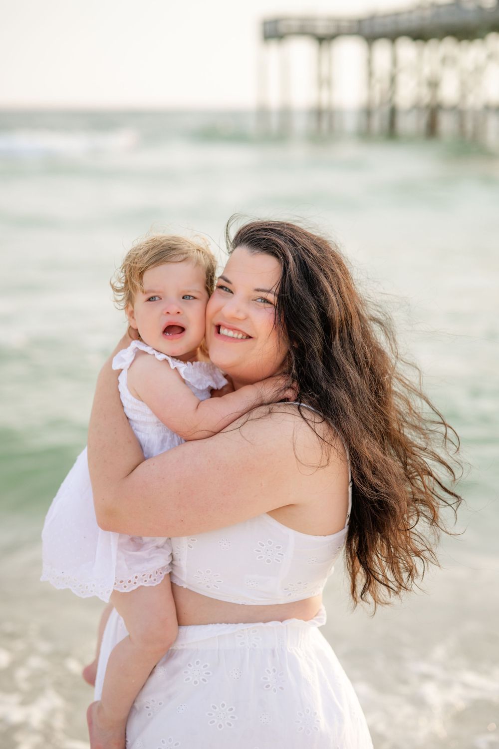 A tender seaside moment between parent and child near the ocean pier.