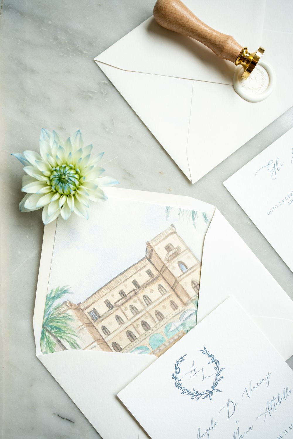 Wedding stationery featuring watercolor illustration of a Mediterranean villa with floral accents.
