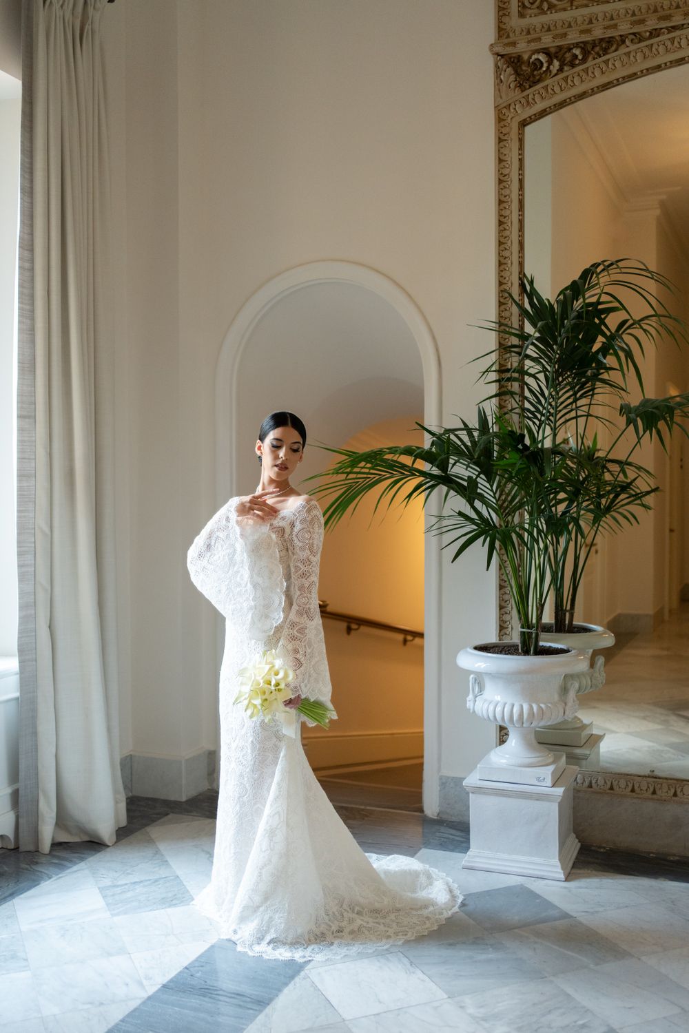 Wedding dress displayed in an ornate white hallway with classical architectural details.