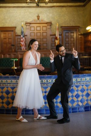 Couple dancing playfully in historic room with decorative blue tile and wood paneling.