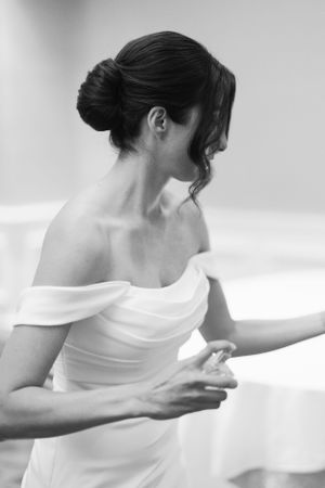 Elegant black and white photo of bride in off-shoulder wedding dress showing graceful neck and updo hairstyle.