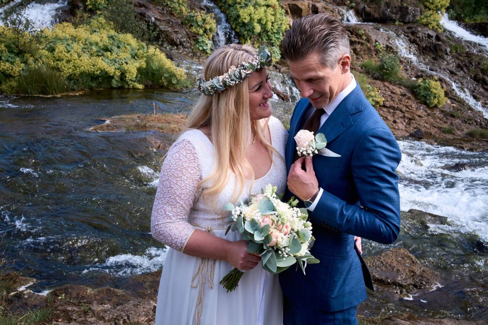A romantic moment captured between newlyweds near a flowing waterfall.