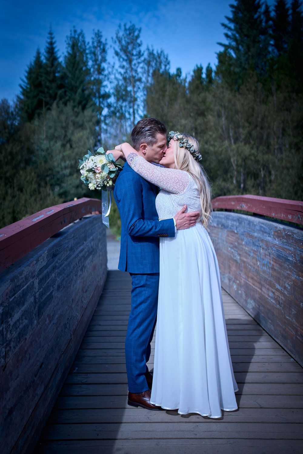 A romantic embrace between newlyweds on a wooden bridge at dusk.