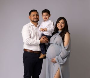 Family portrait session with neutral grey backdrop showing tender moments in coordinated outfits.