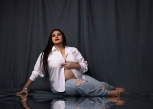Fashion portrait with white shirt and jeans against dark backdrop.