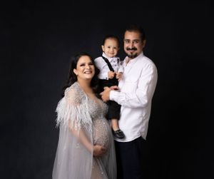 Family portrait session with feathered dress against dark background.
