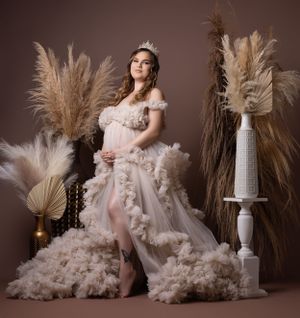 Romantic maternity photos with flowing dress and pampas grass in neutral toned studio setting.
