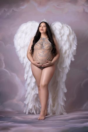 Ethereal maternity portrait with white angel wings and rhinestone bodysuit.