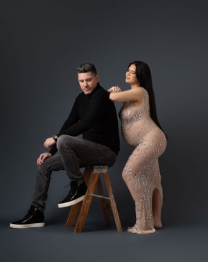 Modern maternity portraits with sparkly dress and casual attire against dark studio background.