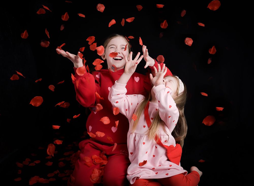 Sisters photography by Nicola in Woodside, capturing petals being thrown in the air, joyful movement, soft studio lighting and timeless