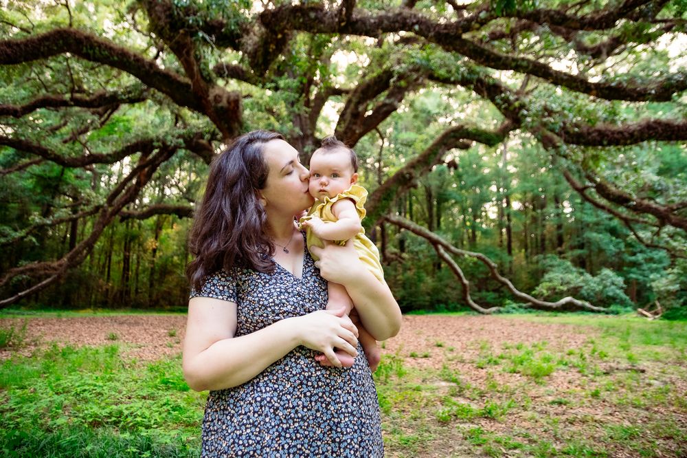 A heartwarming outdoor portrait under sprawling tree branches in a forest setting.