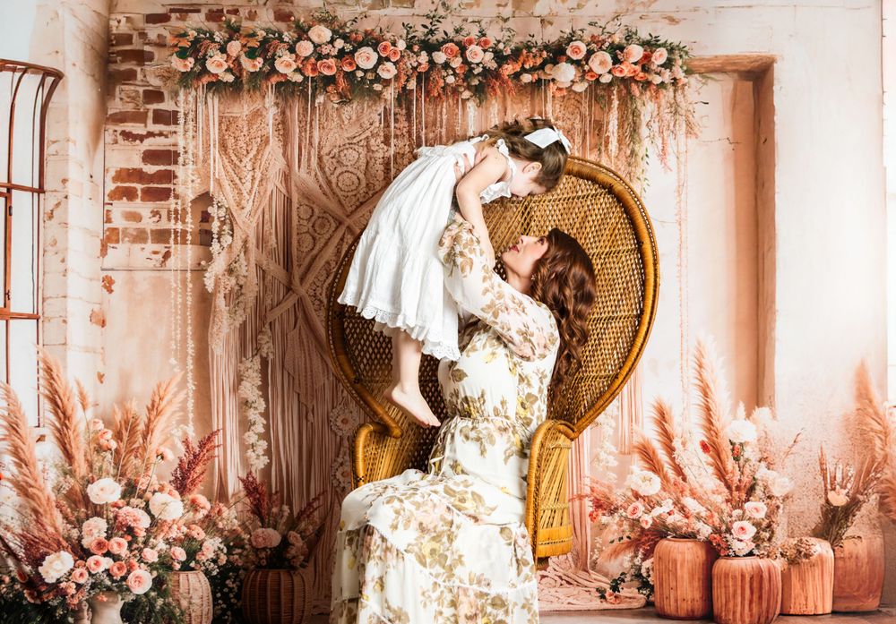 Elegant vintage-inspired scene with peacock chair, floral arch, and soft pink pampas grass decorations in romantic setting.