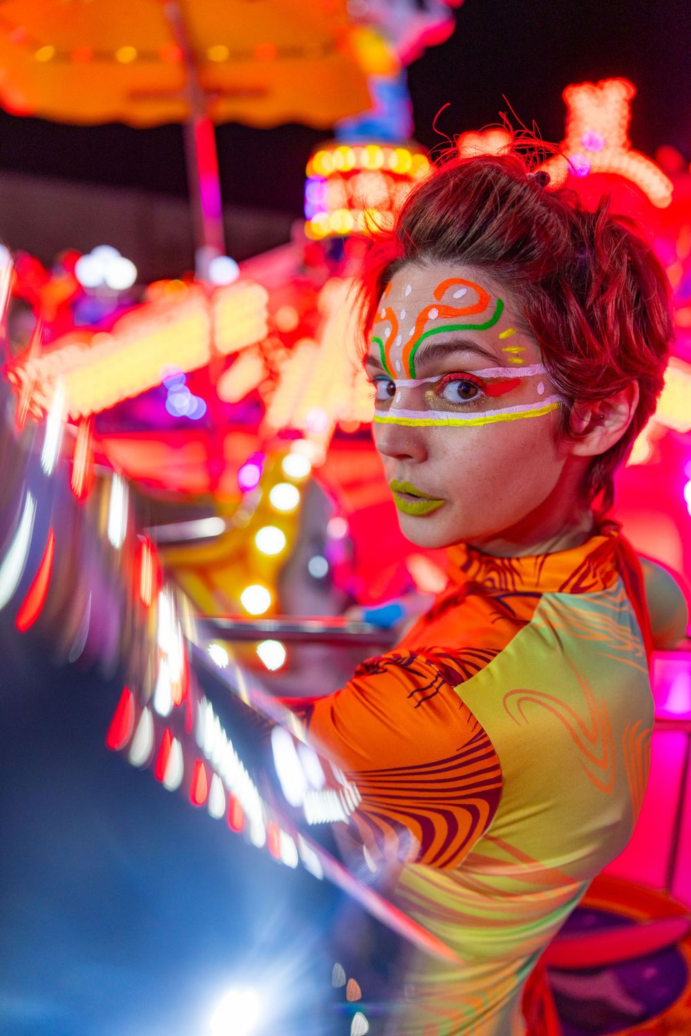 Portrait with orange bodysuit and face paint against carnival lights background.