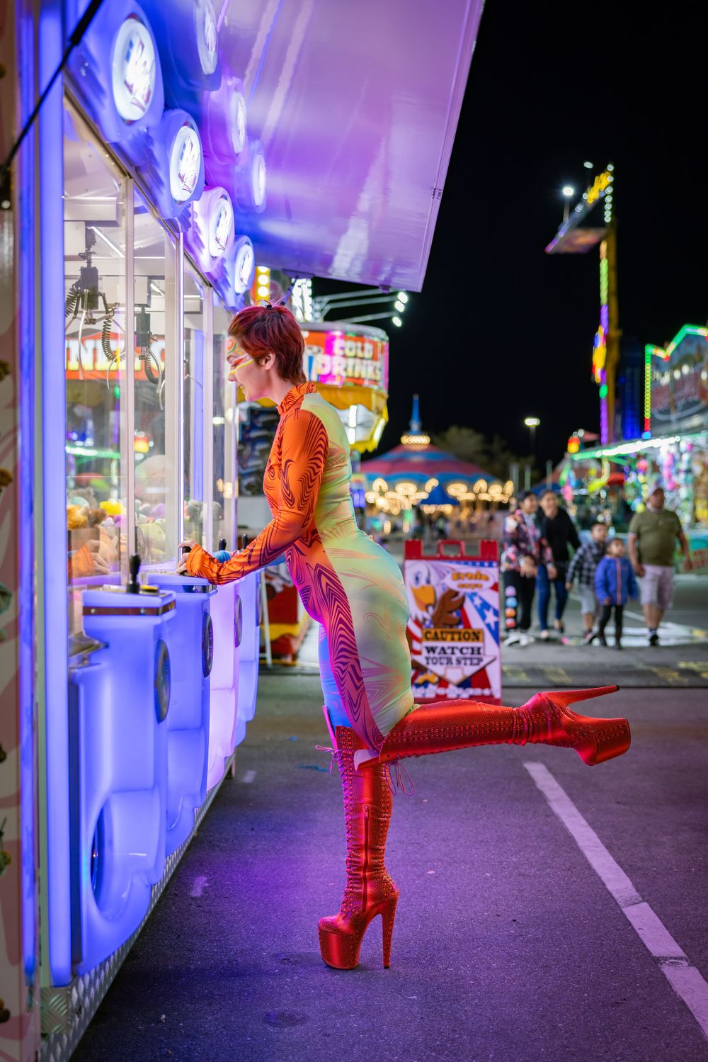 Figure in orange and blue costume poses dramatically by arcade games at night.