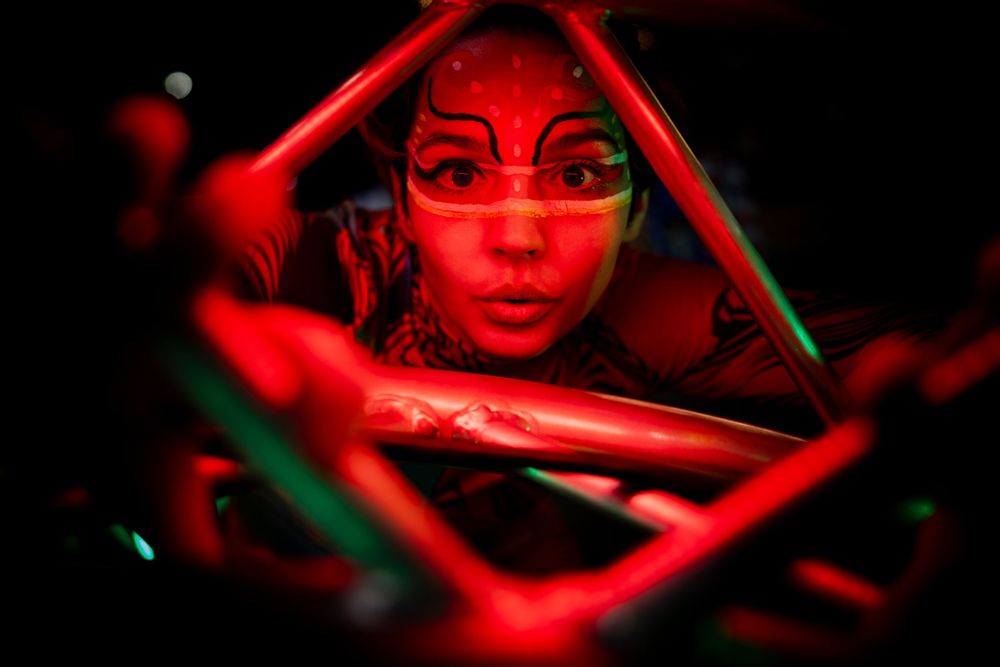 Artistic portrait bathed in dramatic red neon lighting with geometric elements.