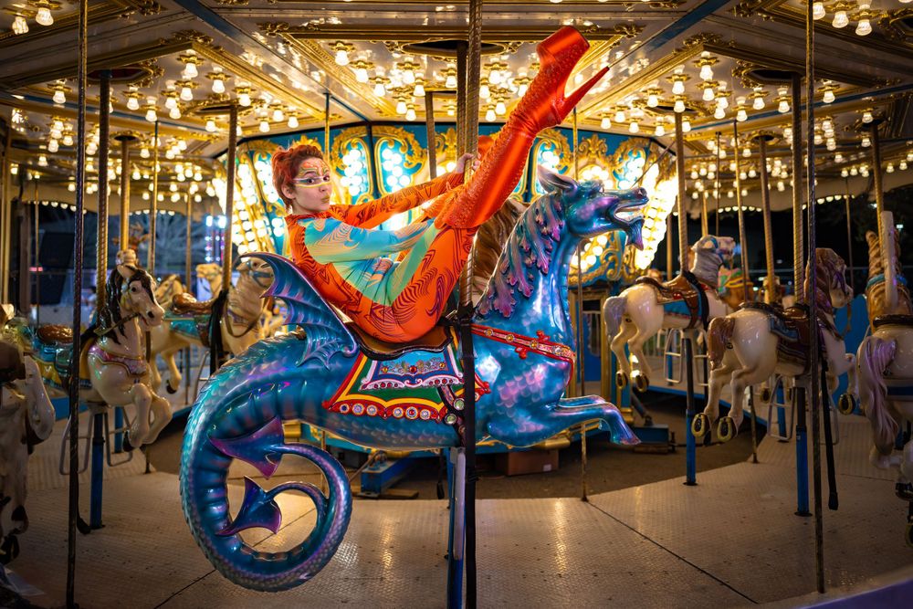 Illuminated carousel with vibrant blue seahorse figure against glowing lights background.