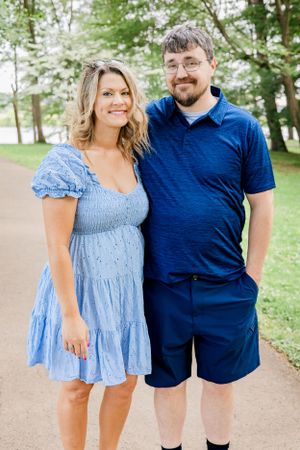 Summer outdoor portrait of couple in blue casual outfits on walking path.