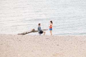 Two people walking and relaxing along a serene ocean shoreline on a peaceful day.