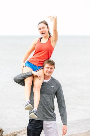 Couple having fun during engagement photo shoot at the beach in bright sunny weather.