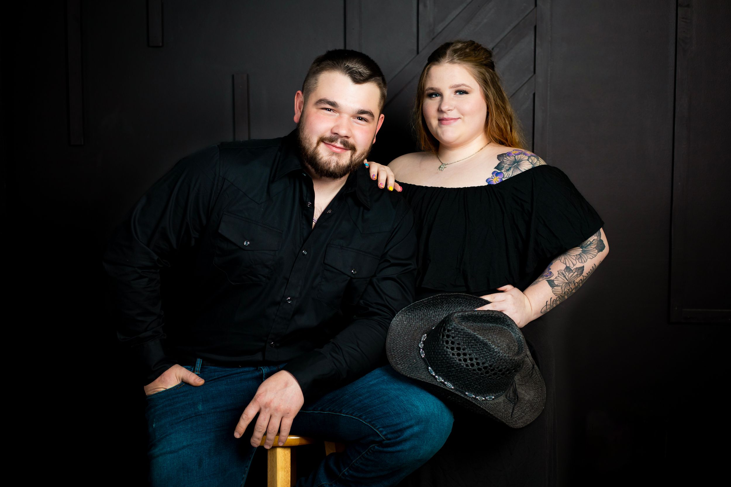 Loving couple in coordinated black outfits pose in an intimate studio portrait.