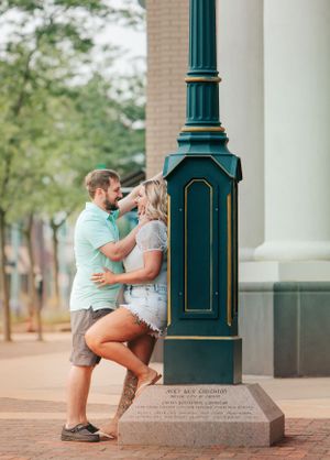 Romantic couple posing by vintage green lamppost in urban setting.