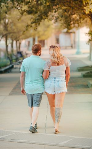 Couple walking together on sidewalk during golden hour.