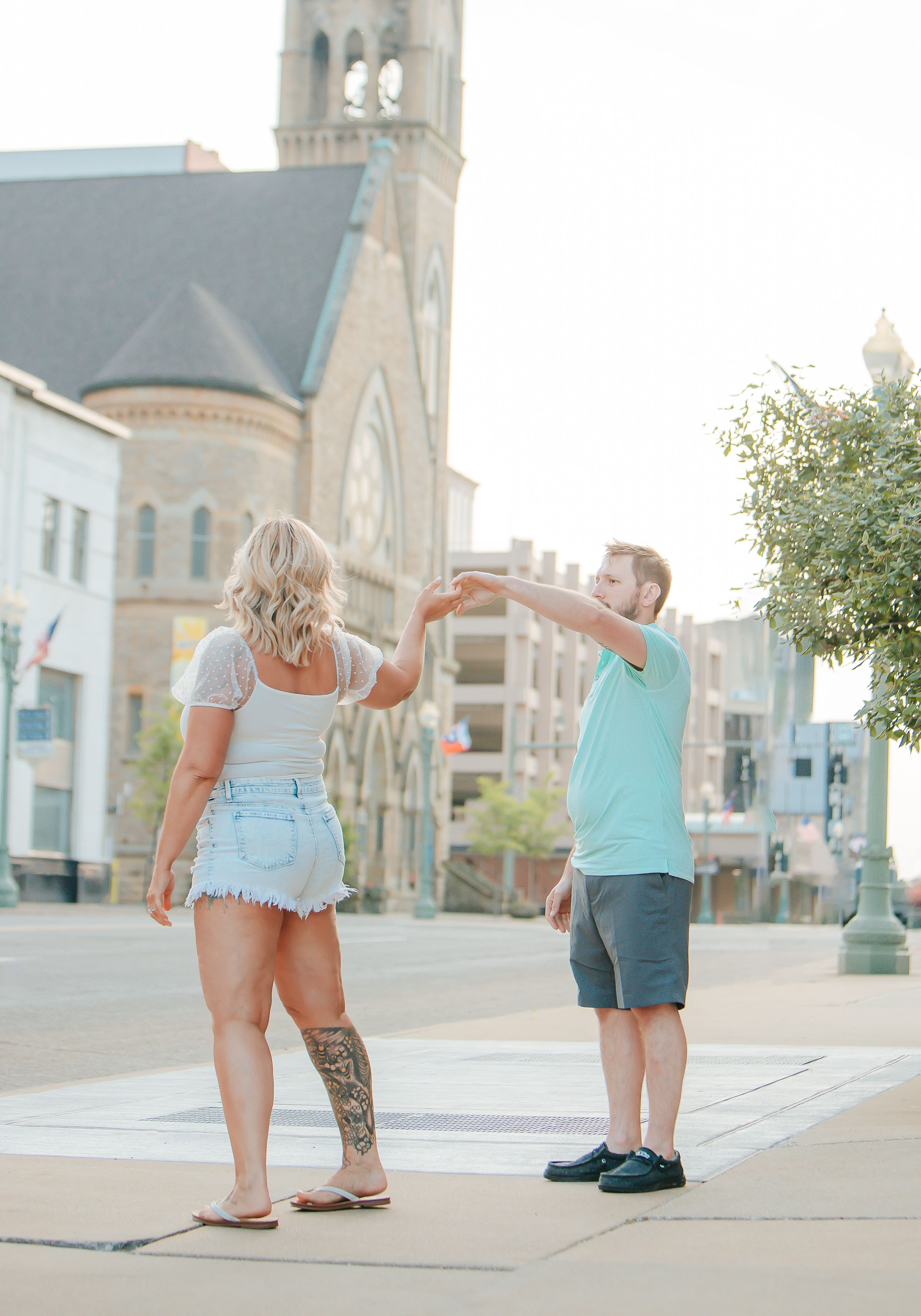 Couple dancing in front of historic church building during sunset.