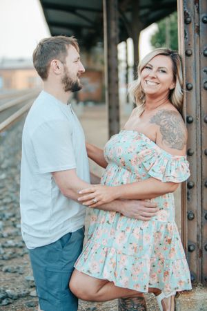 Sweet engagement photo of couple posing by train tracks in matching pastel outfits.