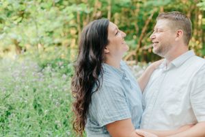 A couple shares a joyful moment outdoors surrounded by greenery.
