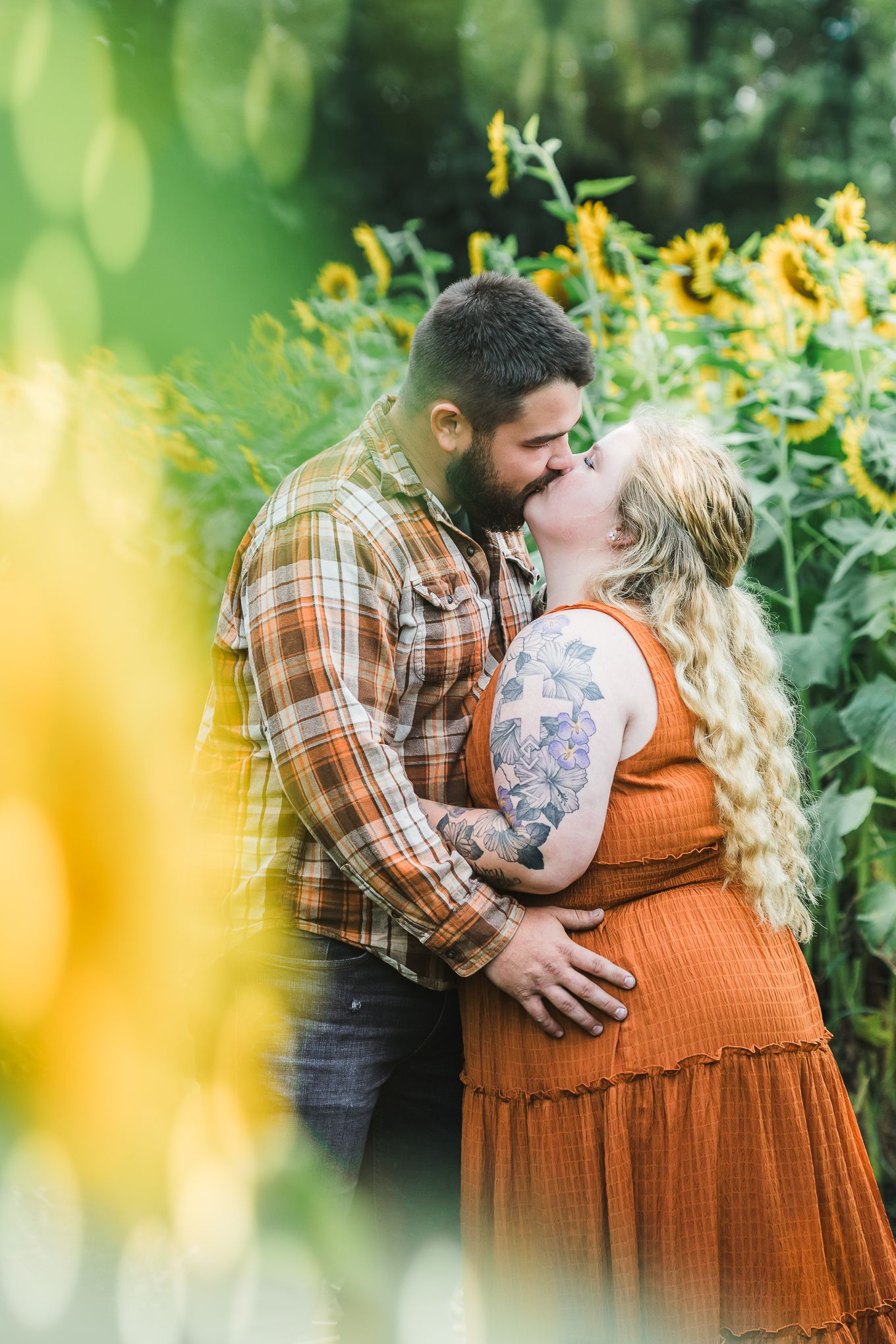 Couple sharing an intimate moment among blooming yellow flowers.