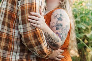 Close-up of embracing couple showing detailed tattoo art and plaid shirt textures.