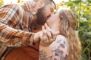 An intimate moment between a couple holding hands among blooming sunflowers.