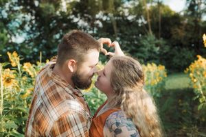 A tender forehead touch moment captured in a sunflower garden setting.