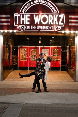 A playful couple poses in front of The Workz entertainment venue sign.