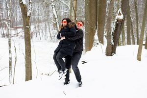 A group sledding and playing together in a snowy winter forest on a hill slope.