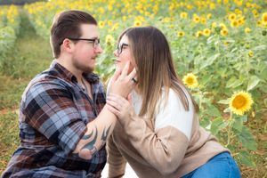 Two people share an intimate moment surrounded by vibrant yellow wildflowers on a sunny afternoon.