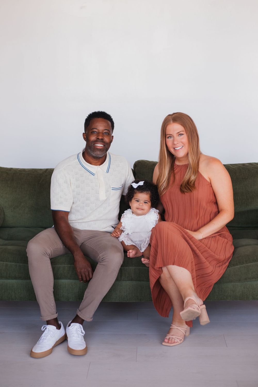 A family sits together on a green couch for a casual portrait session.