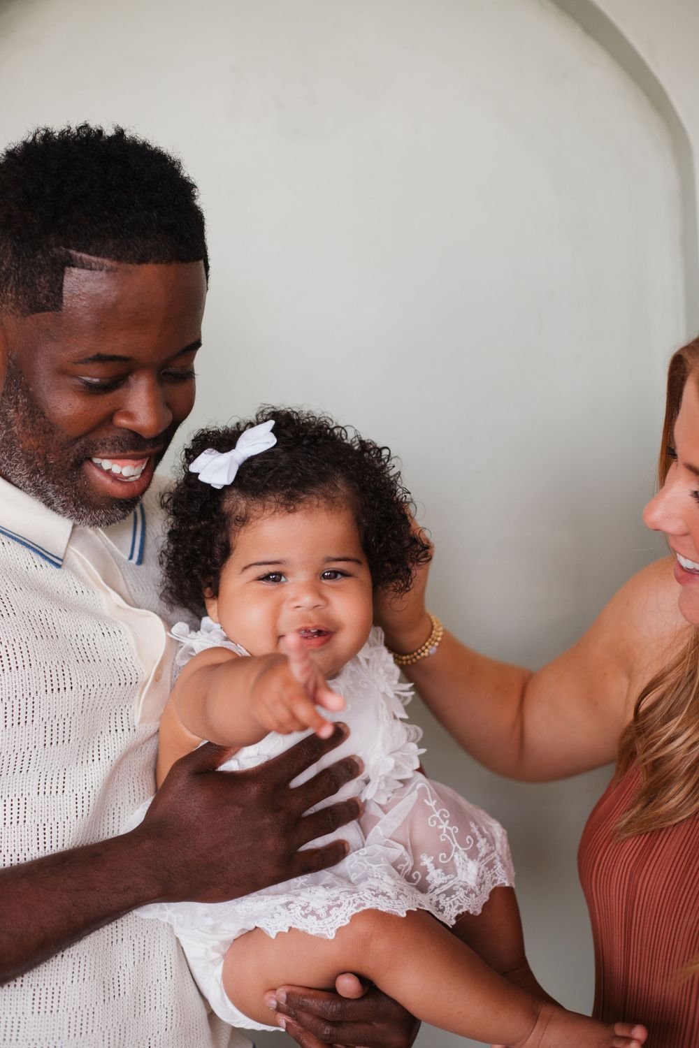 A happy family shares joyful laughter while posing together under an archway.