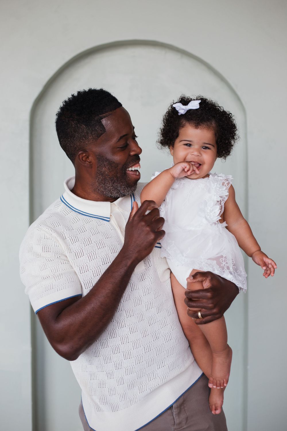 A tender moment shared between parent and child against a white arched background.