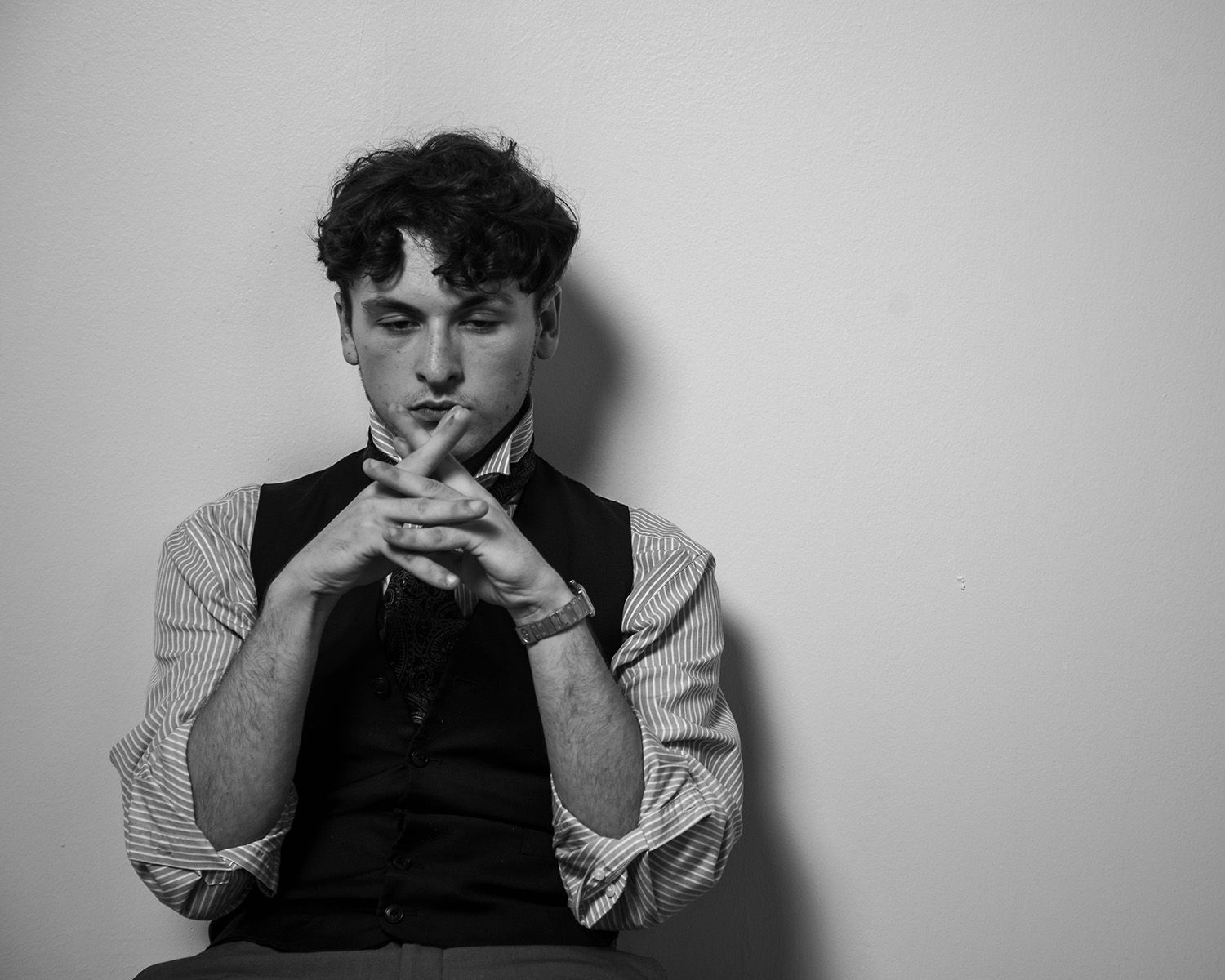 Black and white studio portrait showing person in classic attire with thoughtful expression.