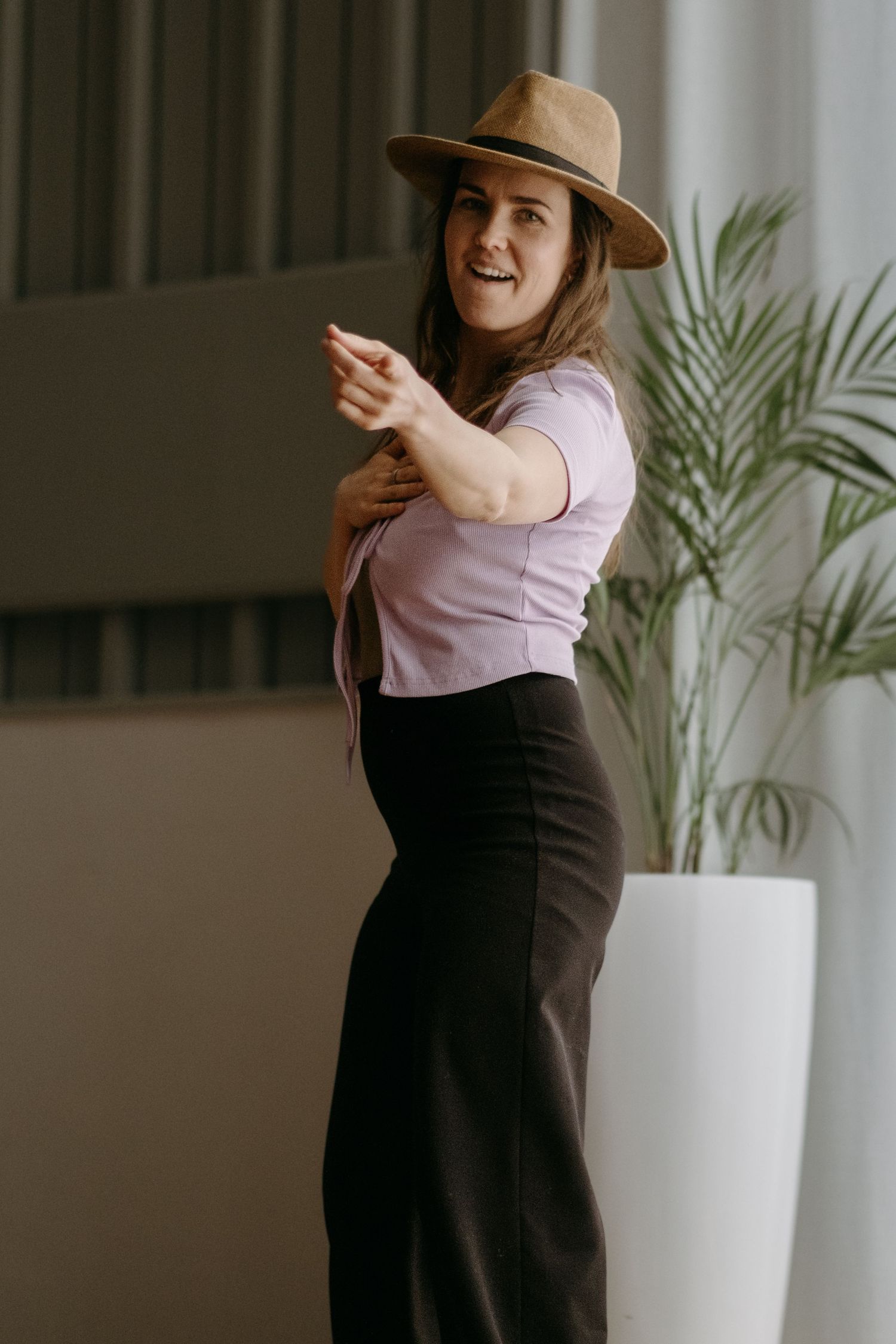 a woman pointing towards a camera and smiling while being captured by Stockholm yoga photographer