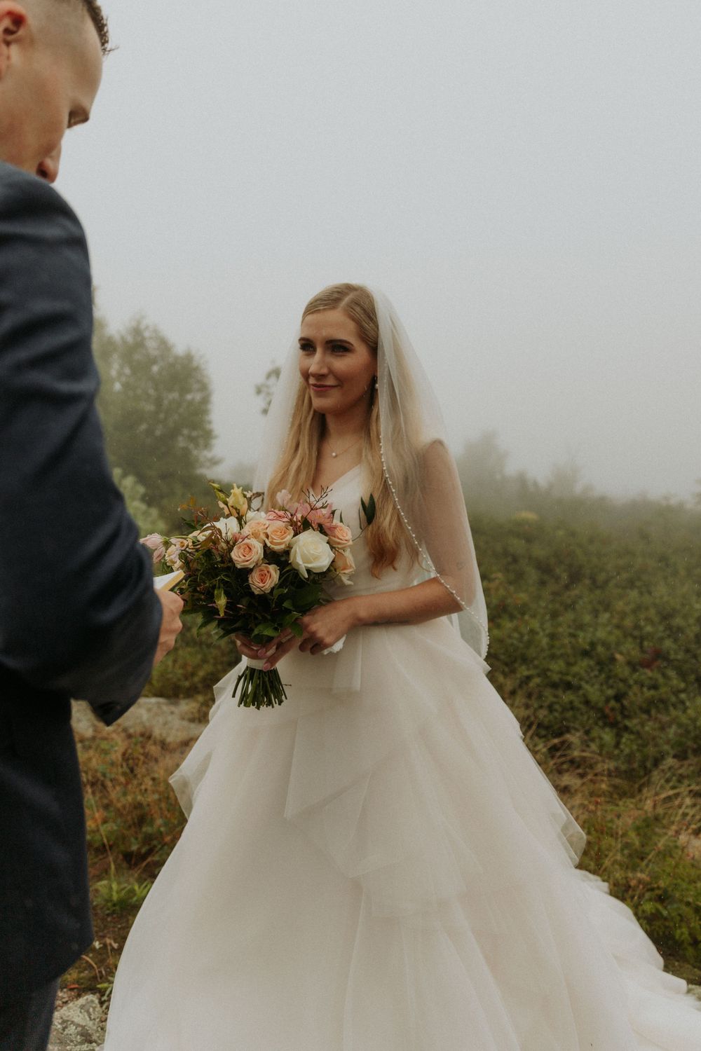 artistically Alexia photography m and j elopement bride listening to grooms vows as it rains