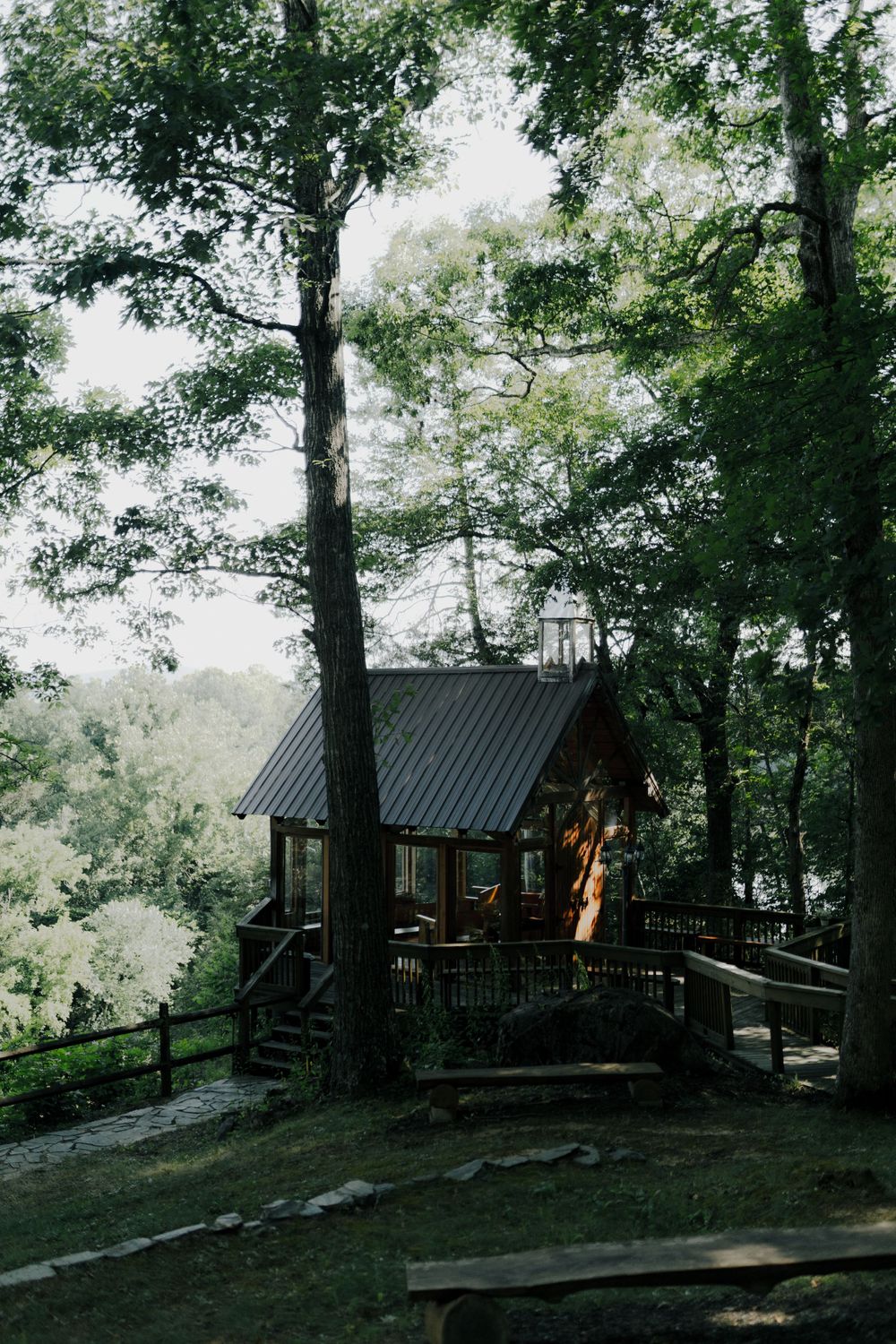 Rustic wooden cabin nestled among green trees on a hillside.