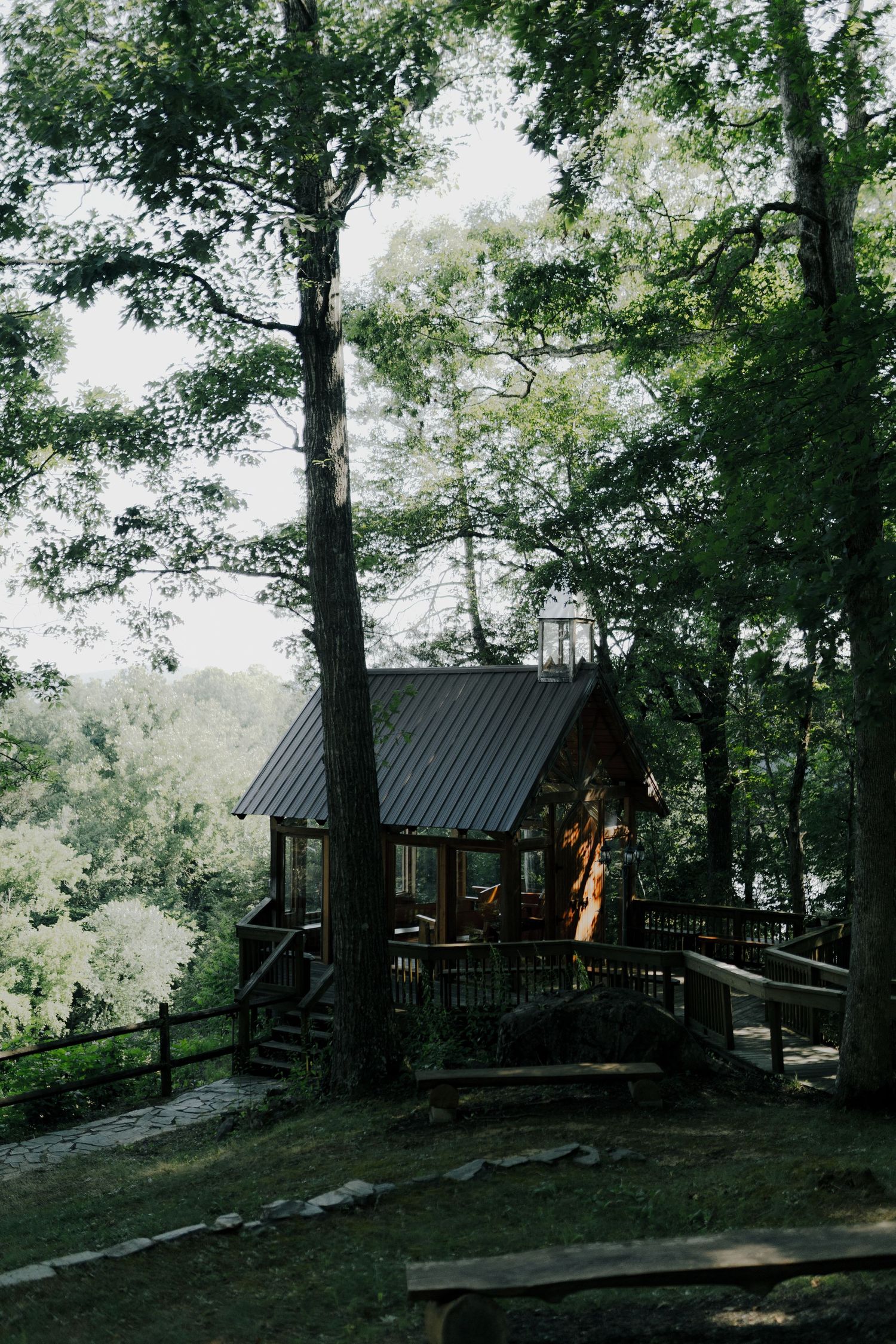 Rustic wooden cabin nestled among green trees on a hillside.
